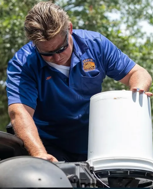 Jeff in his branded blue work shirt performing truck maintenance